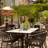Außenterrasse mit gedeckten Tischen, Korbstühlen und Palmen im Best Western Hotel President in Bonn an einem sonnigen Tag.