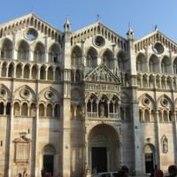 Fassade des Doms von Ferrara mit dreistöckiger romanischer Architektur, verzierten Bogengalerien, runden Rosenfenstern und geschnitzten Steindetails.