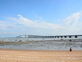 Lange Betonbrücke über die Loire mit zahlreichen kleinen Booten im seichten Wasser bei Ebbe. Sandstrand im Vordergrund.