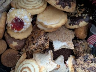 Variety of Christmas cookies including spiral cookies, jam-filled cookies, chocolate-dipped cookies, and star-shaped cookies on a festive plate.