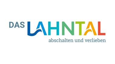 Das Lahntal Logo mit buntem Farbverlauf von Blau bis Rot und deutschem Slogan 'abschalten und verlieben' darunter.