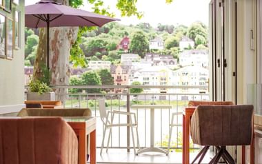 Hotelzimmer-Balkon mit braunen Stühlen und Tisch mit Blick auf Koblenz Stadtbild und Rheinblick.