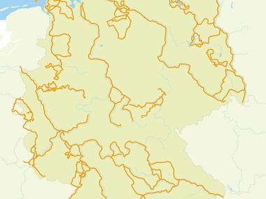 Karte von Deutschland mit Bundesländern in Beige und orangefarbenem Radwegenetz. Nordsee und Ostsee in Blau beschriftet.