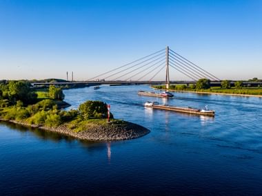Luftaufnahme der Schrägseilbrücke Niederrheinbrücke über den Rhein in Wesel mit Frachtschiffen auf dem Wasser und grünen Ufern.