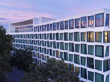 Modernes weißes Atlantic Hotel Münster Gebäude mit geometrischen Fenstern und eckigem Fassadendesign, fotografiert in der Abenddämmerung.