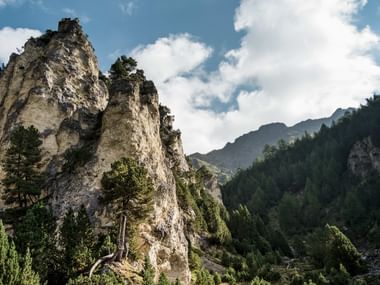 Rocky cliffs in Blenio Valley, Switzerland Dramatic limestone cliffs covered with vegetation in the Blenio Valley, Switzerland. Forested mountains and cloudy sky in background.