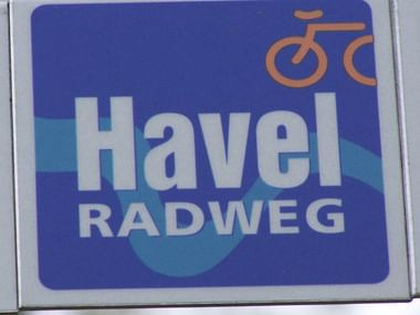 Blaues rechteckiges Schild mit orangefarbenem Fahrradsymbol und weißer Aufschrift 'Havel RADWEG', das den Havel-Radweg markiert.