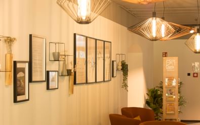 Modern hotel reception with geometric pendant lights, white walls with framed artwork, orange armchairs, and JUFA information display.