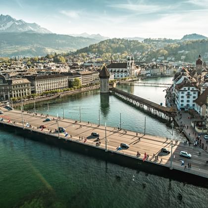 Luftaufnahme von Luzern mit der historischen Kapellbrücke über die Reuss, Altstadt, Bergen und Vierwaldstättersee im Hintergrund.