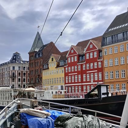 Historischer Nyhavn-Hafen in Kopenhagen mit bunten Stadthäusern aus dem 17. Jahrhundert und traditionellen Holzsegelbooten am Kanal.