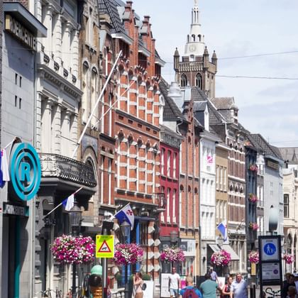 Pedestrian street in Roermond city centre with historic brick buildings, colorful facades, and a church tower in the background.