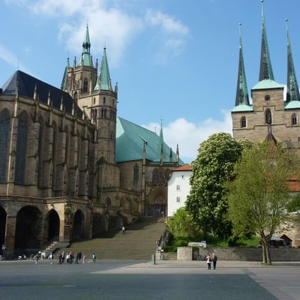 Erfurter Dom und Severikirche Erfurter Dom mit grünem Kupferdach und Severikirche mit drei Türmen auf dem Domplatz unter blauem Himmel mit weißen Wolken.