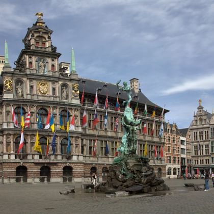 Antwerpens Grote Markt mit historischen Gebäuden Panoramablick auf Antwerpens Grote Markt mit dem verzierten Renaissance-Rathaus mit bunten Flaggen und Gildenhäusern mit Treppengiebeln.