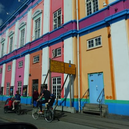 Bunte Häuser in Kopenhagen Reihe bunter historischer Häuser in Kopenhagen mit rosa, orangen, gelben und weißen Fassaden. Radfahrer und Fußgänger auf der Straße.