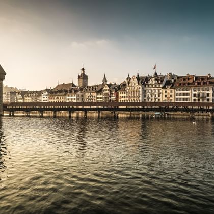 Historische Kapellbrücke mit achteckigem Wasserturm am Vierwaldstättersee, mit bunten historischen Gebäuden entlang der Uferpromenade.