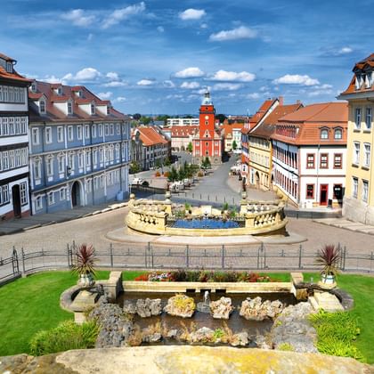 Gotha main market square with historic buildings Aerial view of Gotha's main market square with colorful historic buildings, central fountain, and red town hall tower under blue sky.