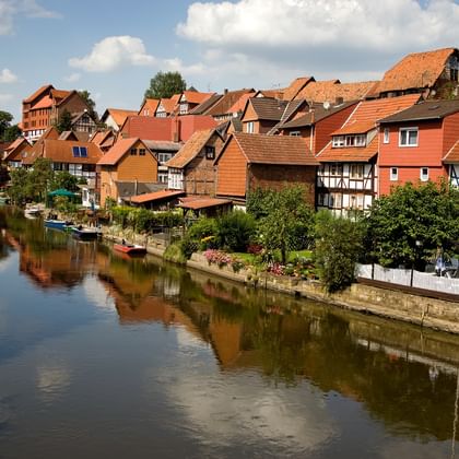 Bad Sooden-Allendorf am Flussufer Historische Fachwerkhäuser mit roten Ziegeldächern säumen die Werra in Bad Sooden-Allendorf. Die bunten Gebäude spiegeln sich im ruhigen Wasser.