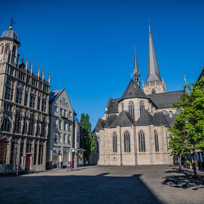 Historic market square in Wesel with Gothic church featuring twin spires, ornate town hall with decorative facade, and cobblestone plaza under blue sky.
