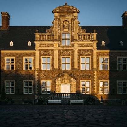 Historisches Schloss Ahaus im Münsterland mit ornamentaler Barockfassade, rotem Backsteinbau und dekorativem Haupteingang im warmen Abendlicht.