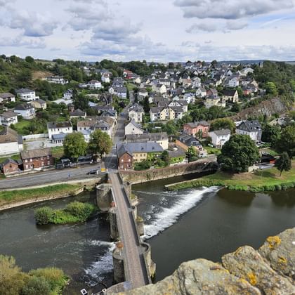 Aerial view from Runkel Castle of a stone bridge crossing the Lahn River with weir, overlooking the town of Runkel with houses and green hills.